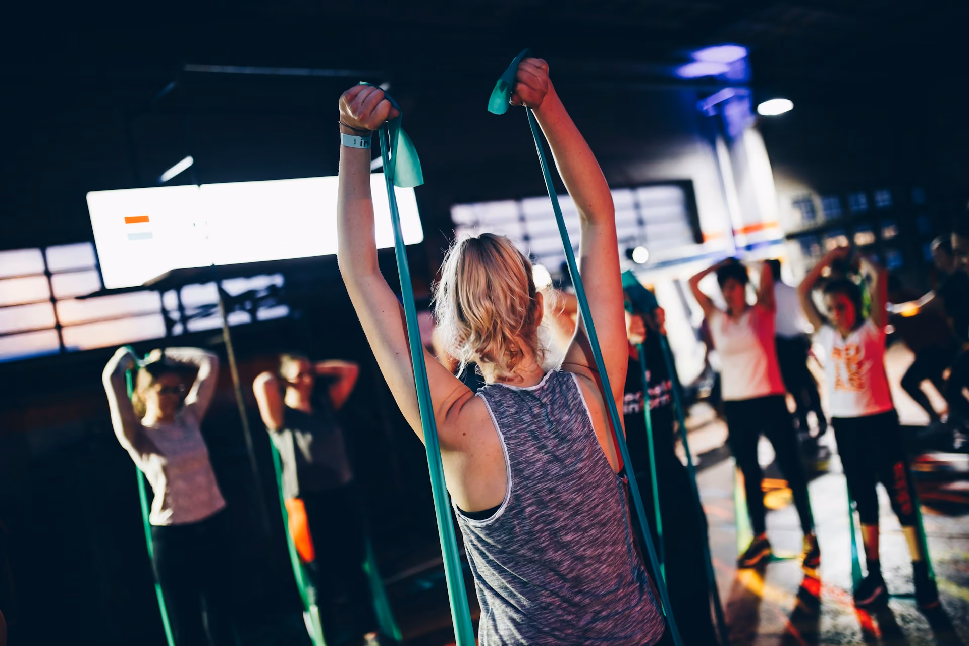 A group fitness class where an instructor leads a handful of people in the use of resistance bands.