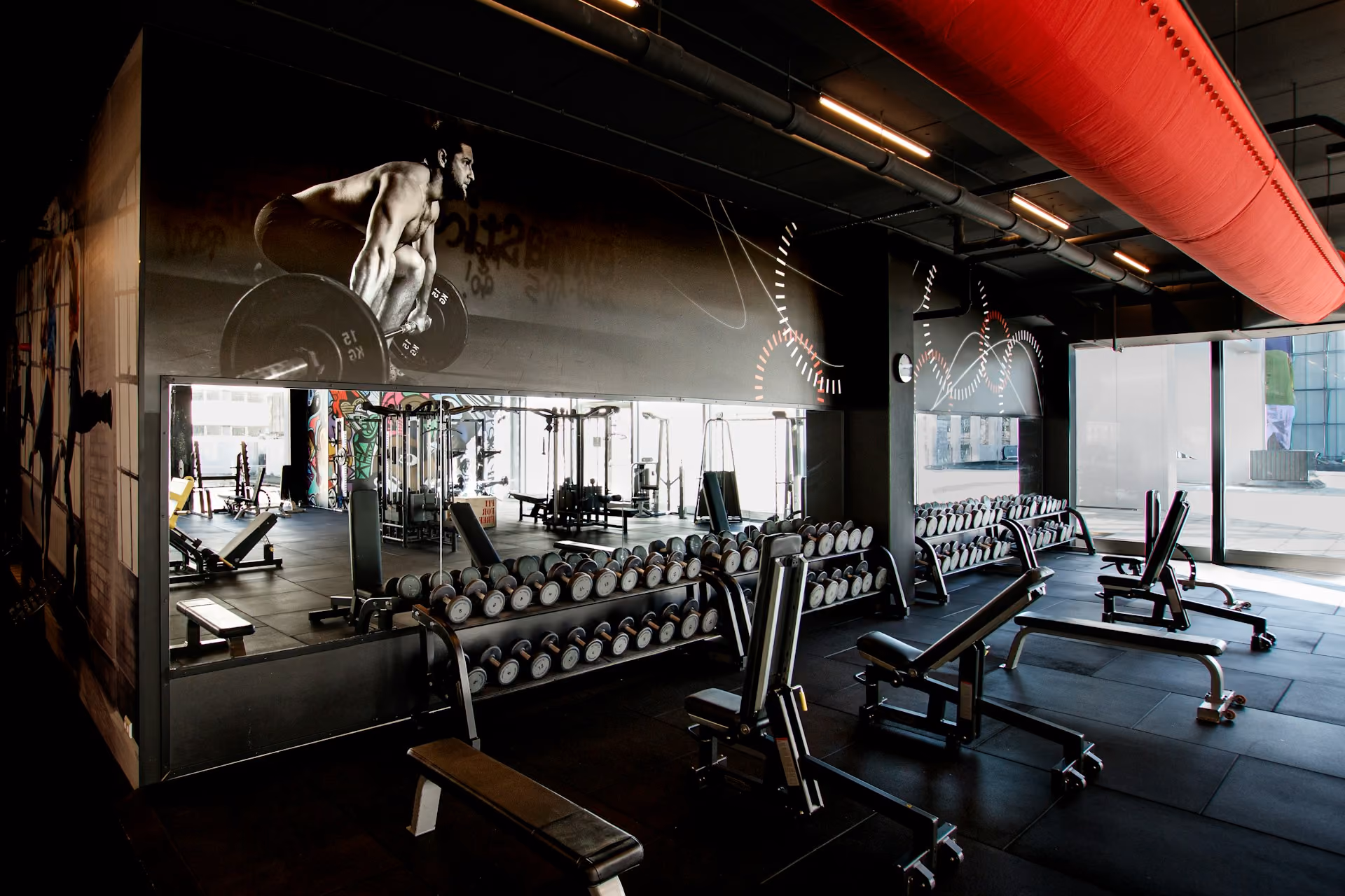 An empty gym with several incline benches and dumbbells on a rack. Gym equipment is costly and just one of many factors when applying for financing for your new franchis