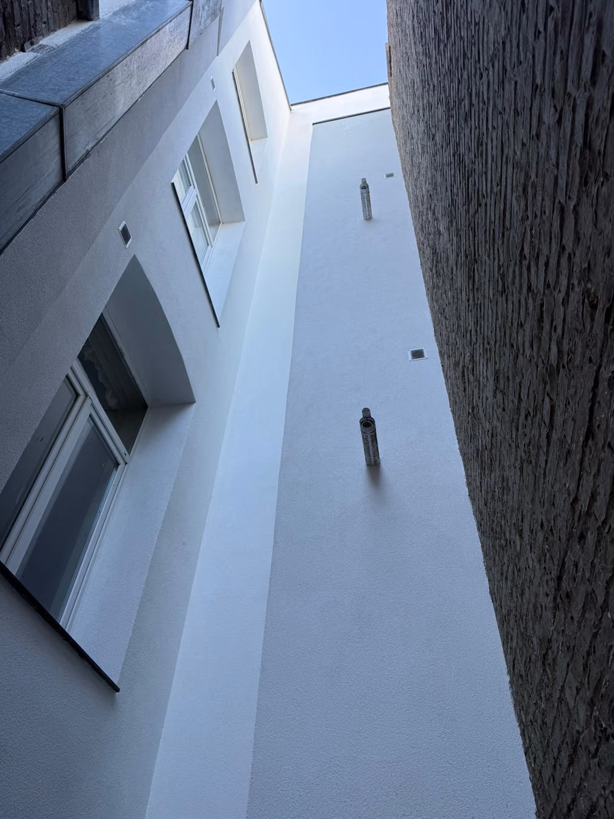 Perspective verticale d’une façade rénovée vue depuis une cour intérieure.