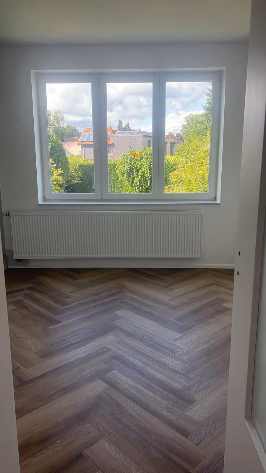 Chambre rénovée avec parquet en chevrons et double fenêtre.
