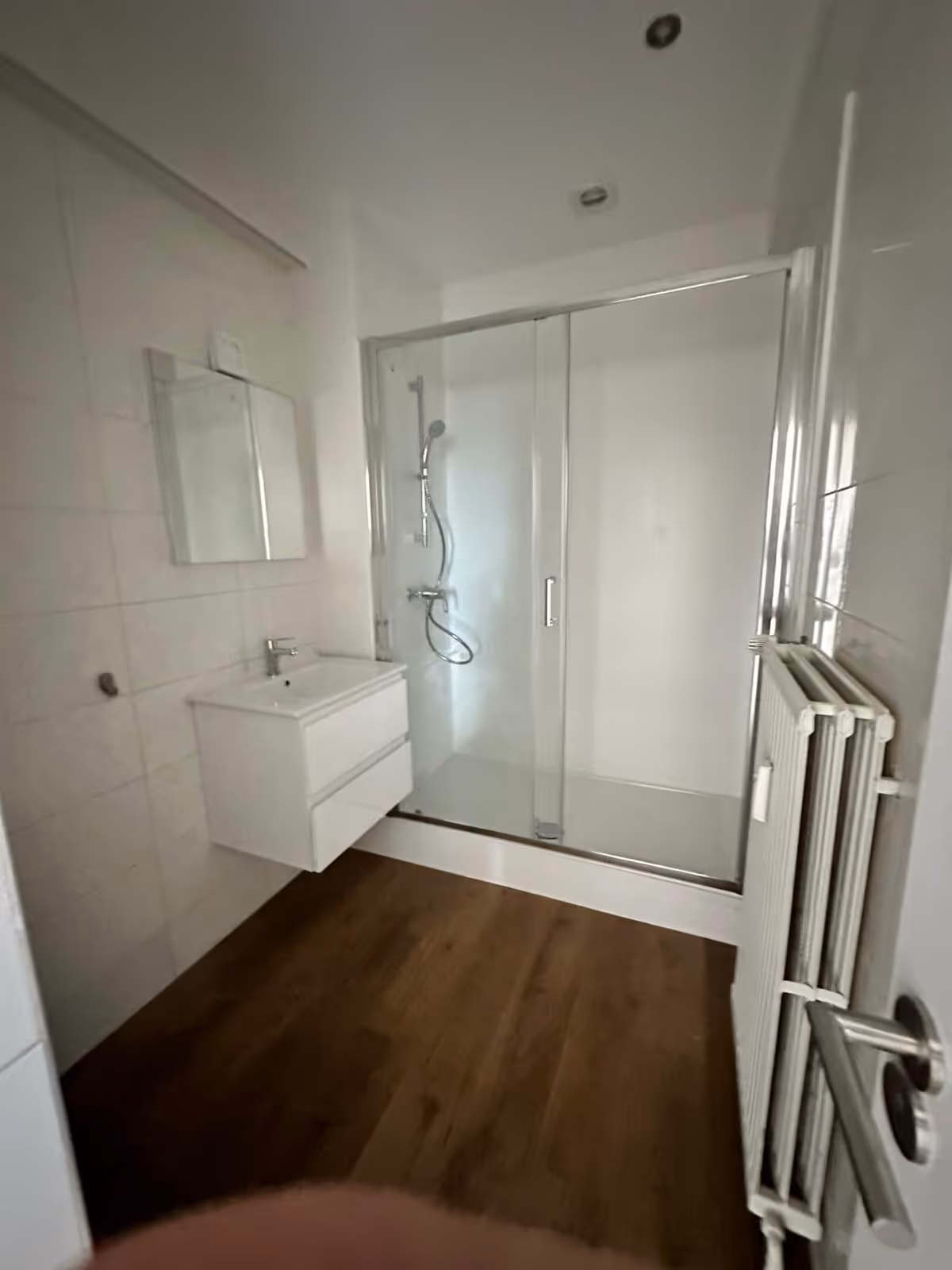 Salle de bain rénovée avec carrelage mural blanc et radiateur design.
