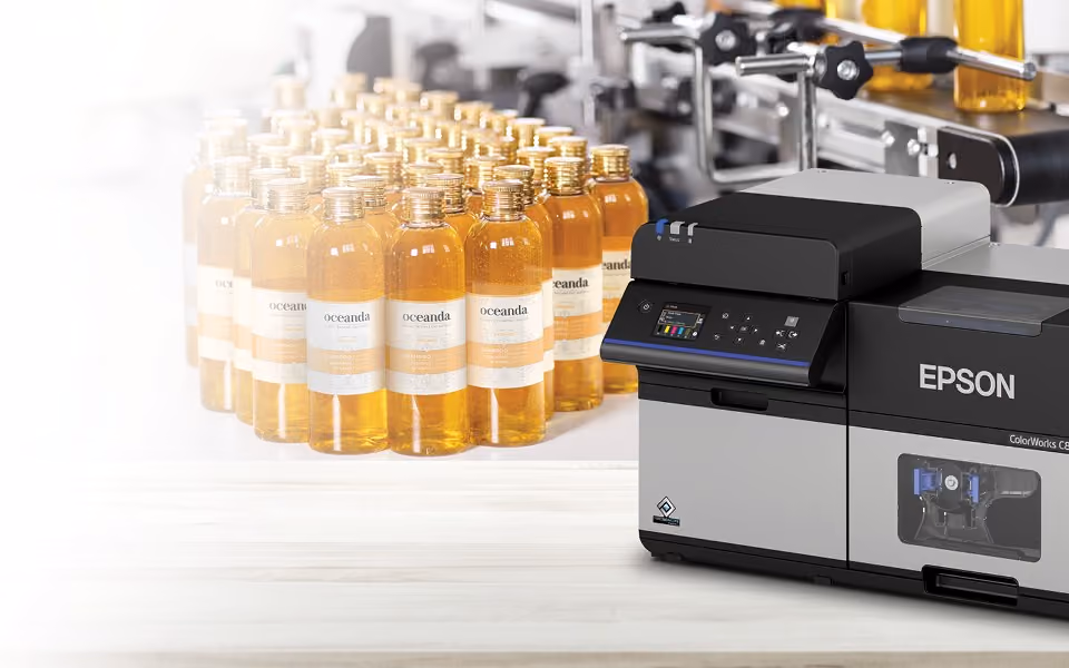 Labelled bottles coming off a filling line beside a ColorWorks printer