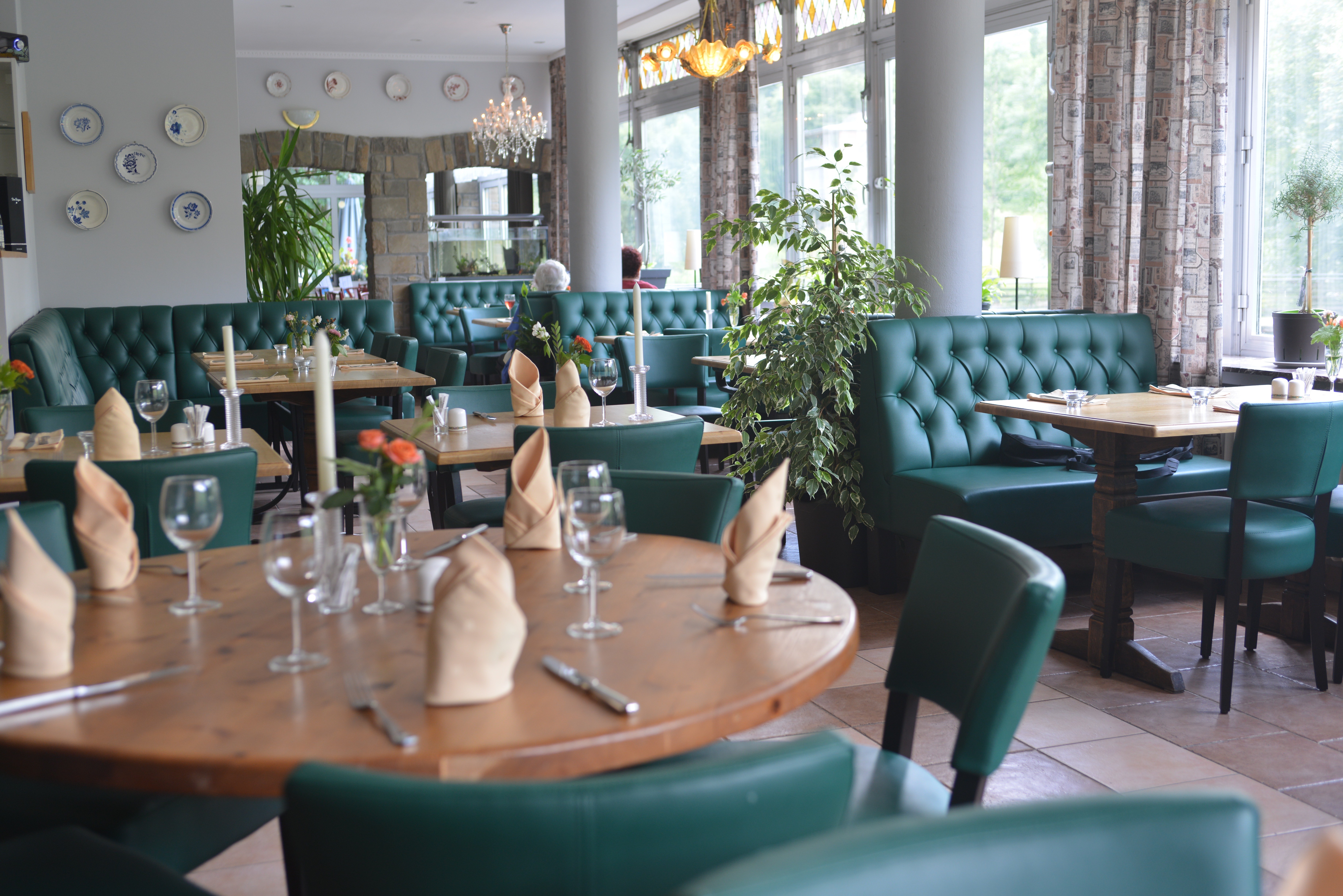 Cozy restaurant interior with green seating and wooden tables