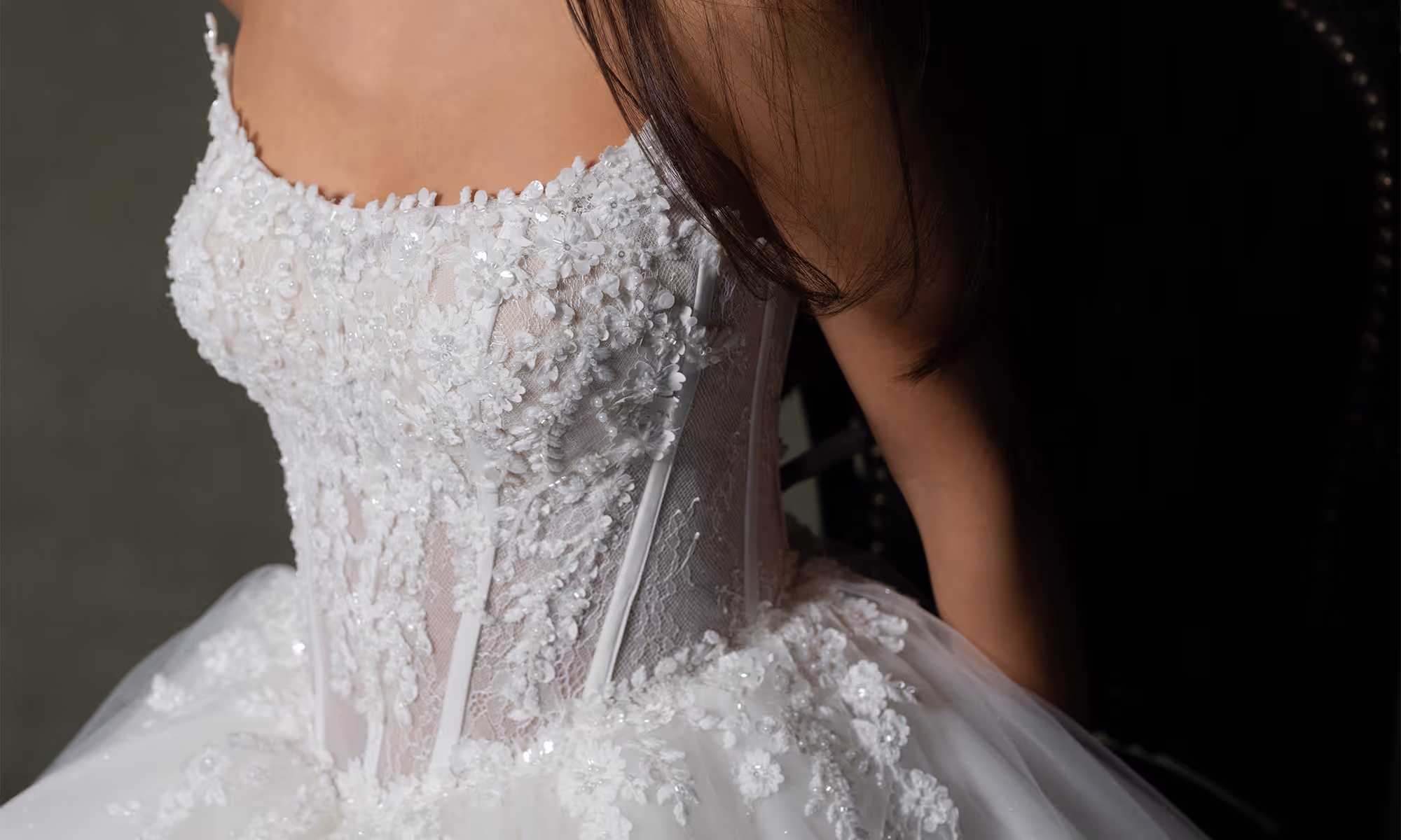 Close-up van een witte trouwjurk met delicate bloemrijke kant en pailletten op de lijfje.