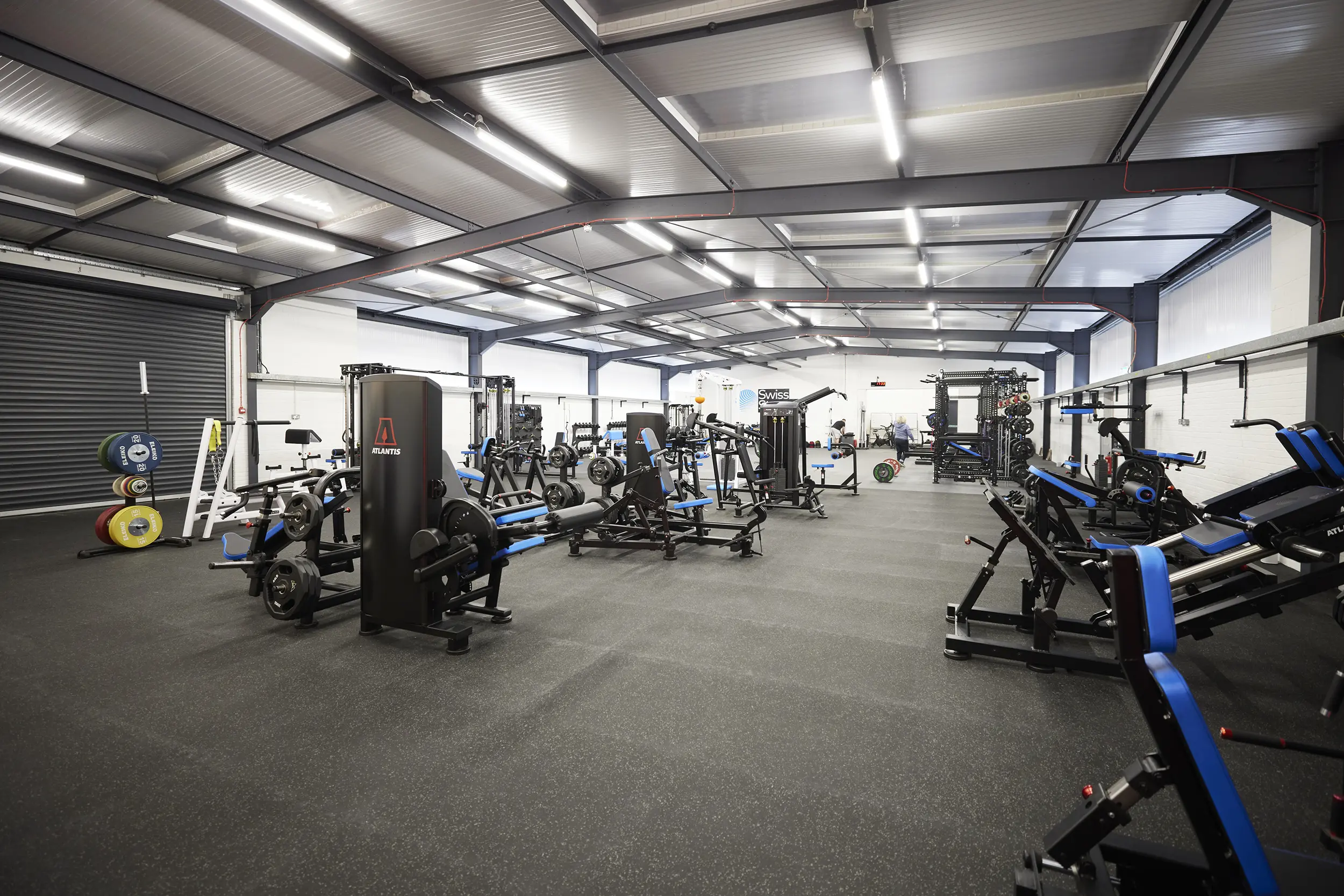 Spacious, well-lit gym with multiple weight machines and free weights organized across the floor.