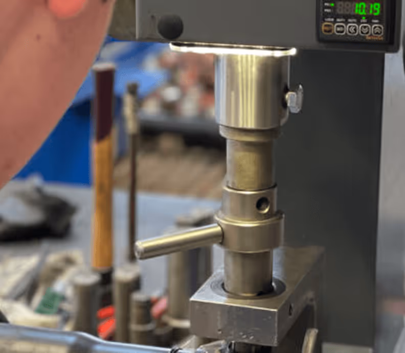 Person bedient Bohrmaschine in Werkstatt, Fokus auf Metallwerkzeug und Bedienfeld.