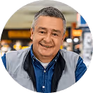 Mann mittleren Alters lächelt in Arbeitskleidung in Geschäftsumgebung.