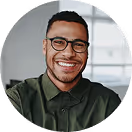 Lächelnder Mann mit Brille und grünem Hemd vor verschwommenem Fensterhintergrund.