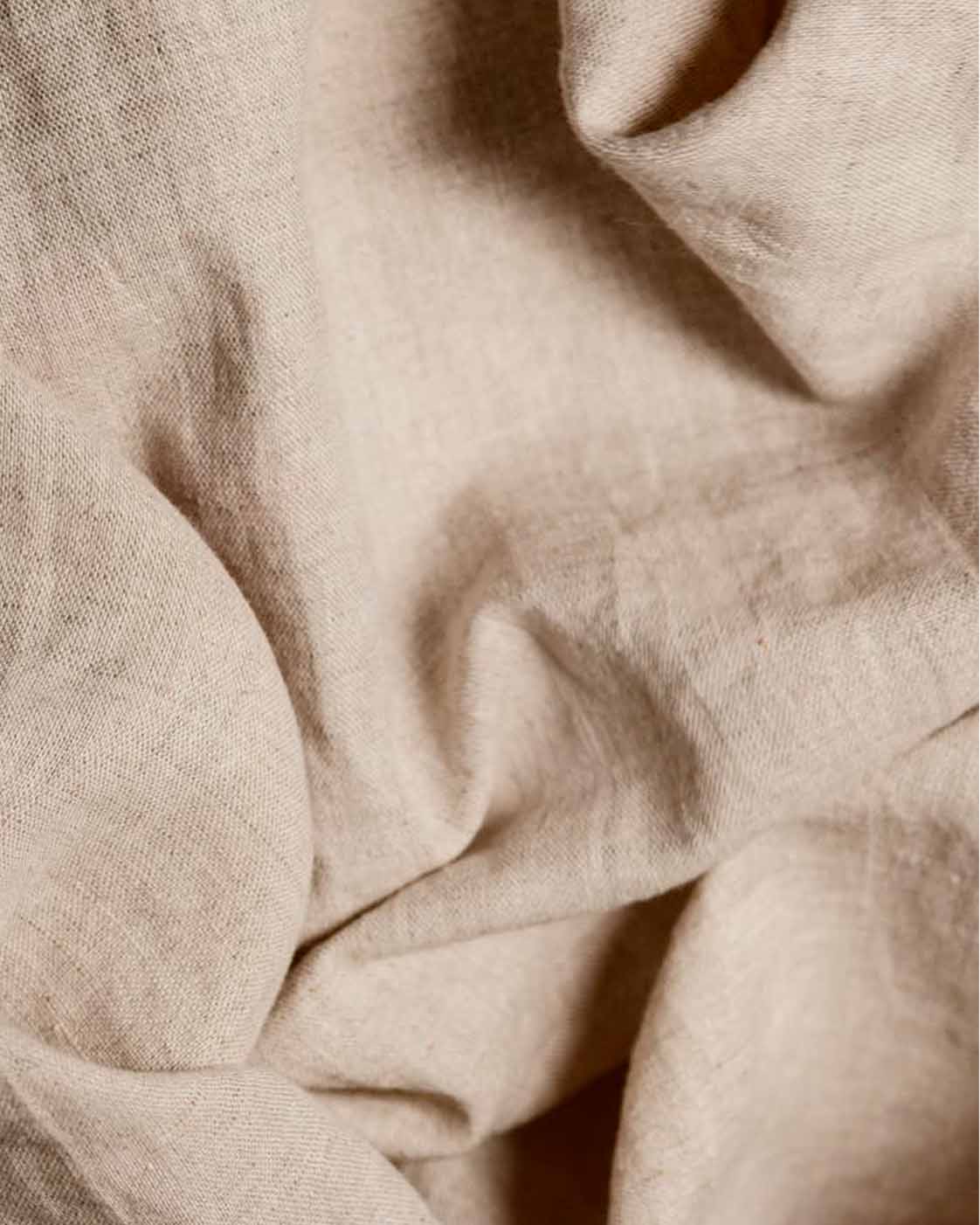 Close-up of natural beige linen fabric showing the lightweight texture and soft drape of the material.