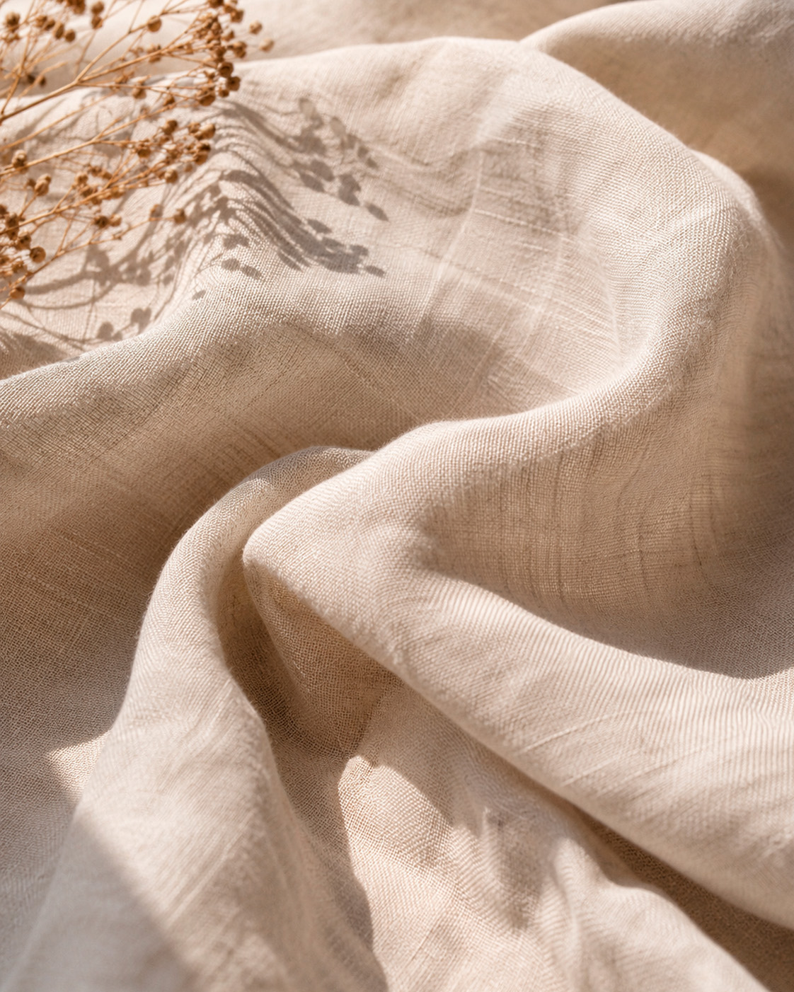 Close-up of natural beige linen fabric showing its lightweight weave, soft texture, and relaxed summer drape.
