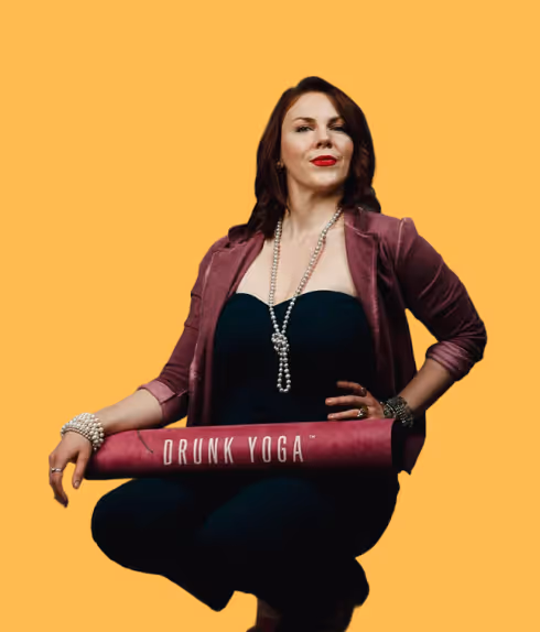 Woman dressed in black and purple holding a pink yoga mat labeled 'DRUNK YOGA' against an orange background.
