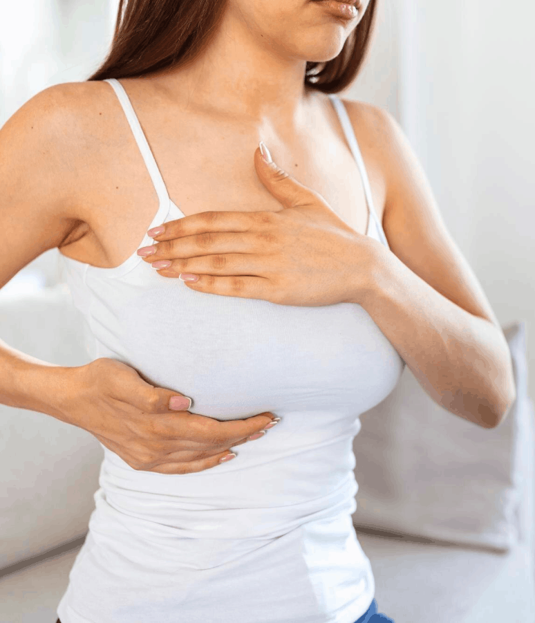 Femme en débardeur blanc se tenant la poitrine, effectuant un auto-examen des seins.