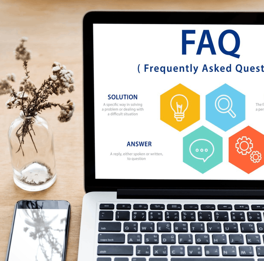 Ordinateur portable affichant une page FAQ avec icônes colorées, à côté d'un téléphone et d'un vase avec des fleurs séchées.