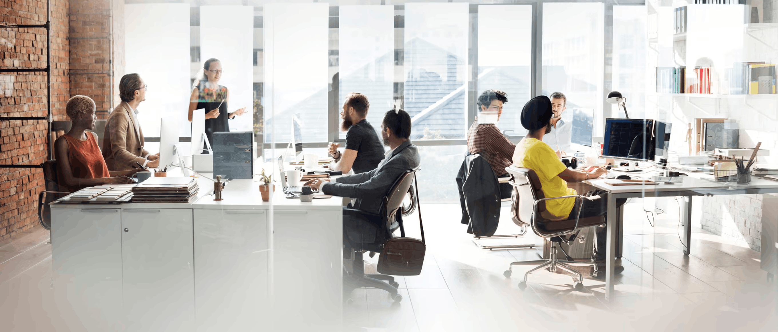 Équipe diverse en réunion et travaillant dans un bureau moderne avec de grandes fenêtres.