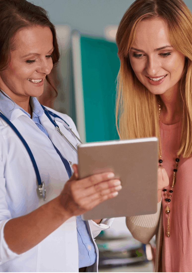 Médecin et patiente souriantes regardant une tablette numérique ensemble.