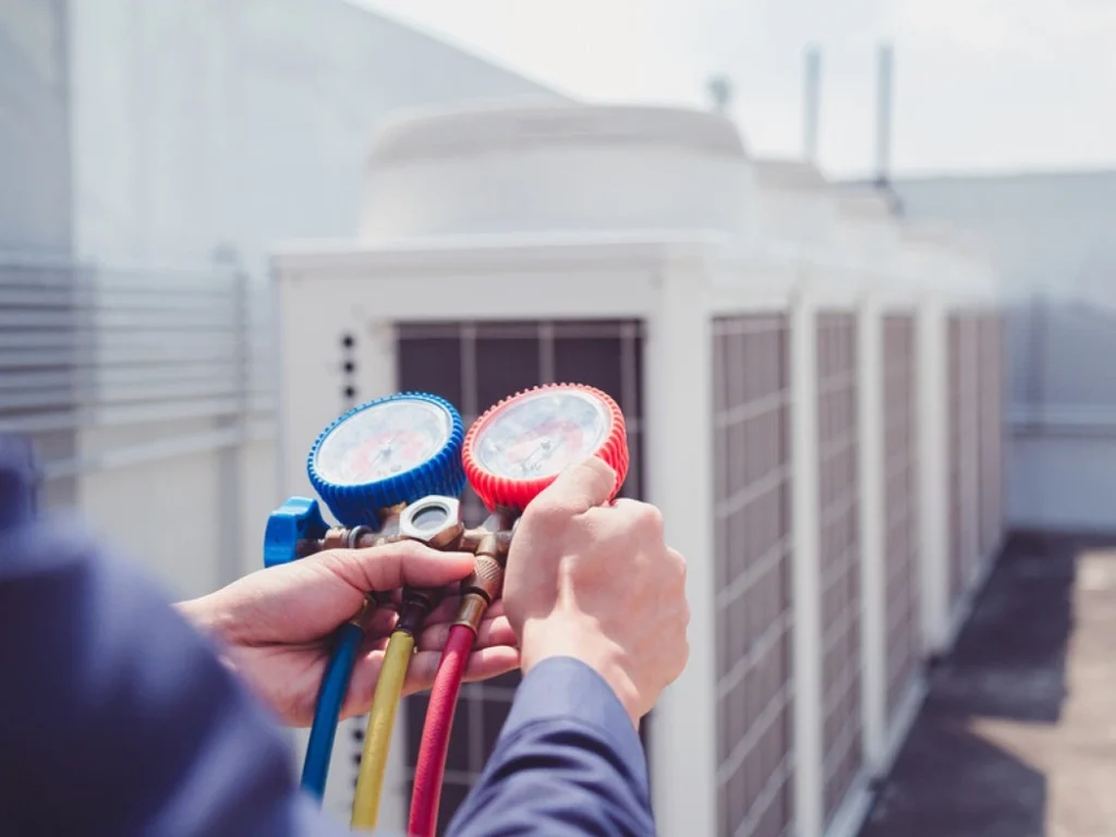 Technician using pressure gauges on HVAC system for commercial installation and maintenance in Independence, MO.