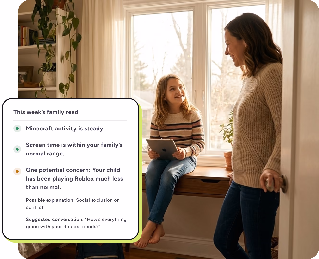 Mother talking with smiling daughter holding a tablet by a window in a cozy room with a plant.