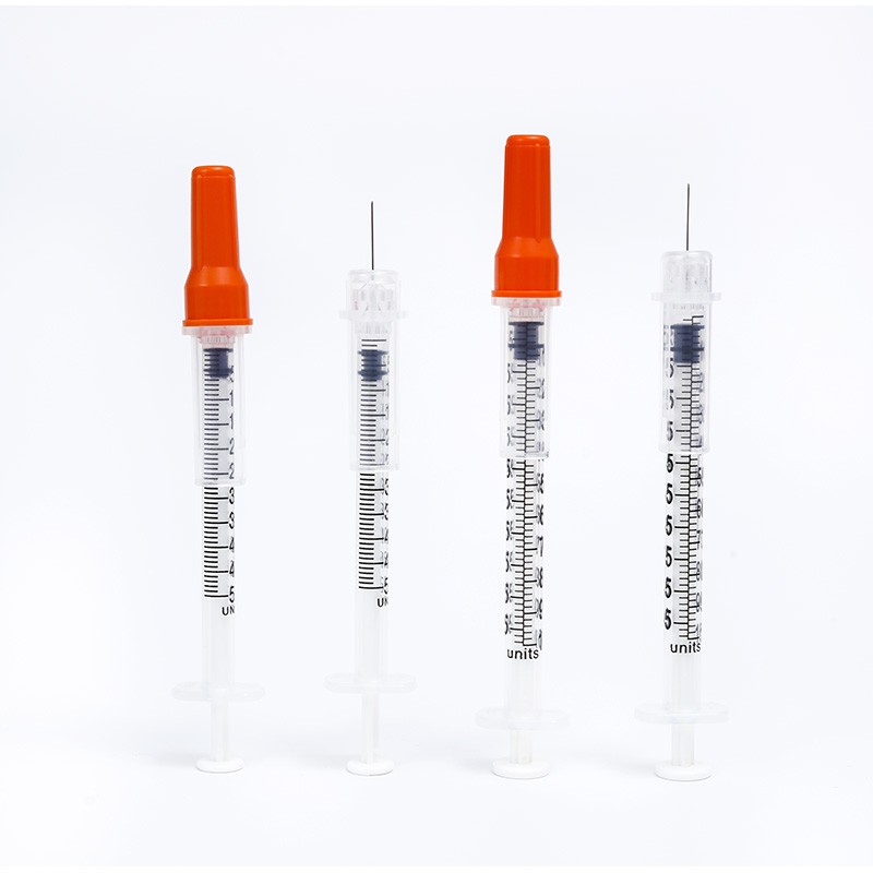 Four insulin syringes with orange caps and needles. One syringe is open. Medical supply image.