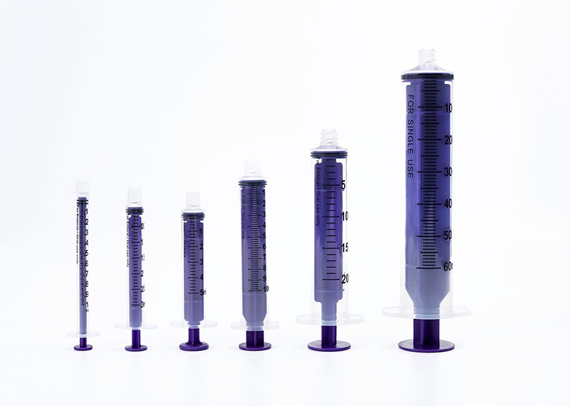 Collection of purple syringes lined up from smallest to largest size, each with a measurement scale and plunger.