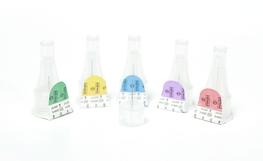 Five different colored insulin pen needles in a row, each with a different color label on the front.
