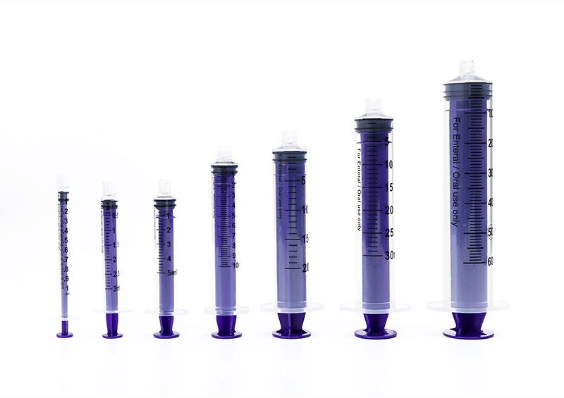 Seven purple and clear medical syringes of varying sizes on display, highlighting dosage measurements.