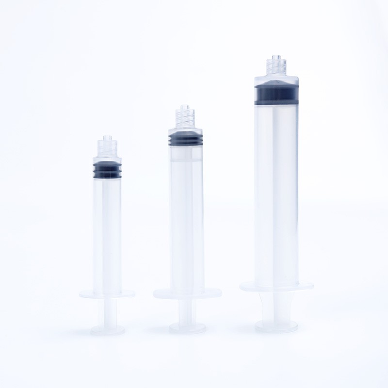 Three different sized syringes. The syringes are standing upright in a row. They are clear with black plungers.