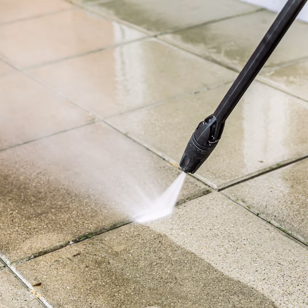 Hochdruckreiniger entfernt Schmutz von einer Steinfläche und macht sie sichtbar sauberer.