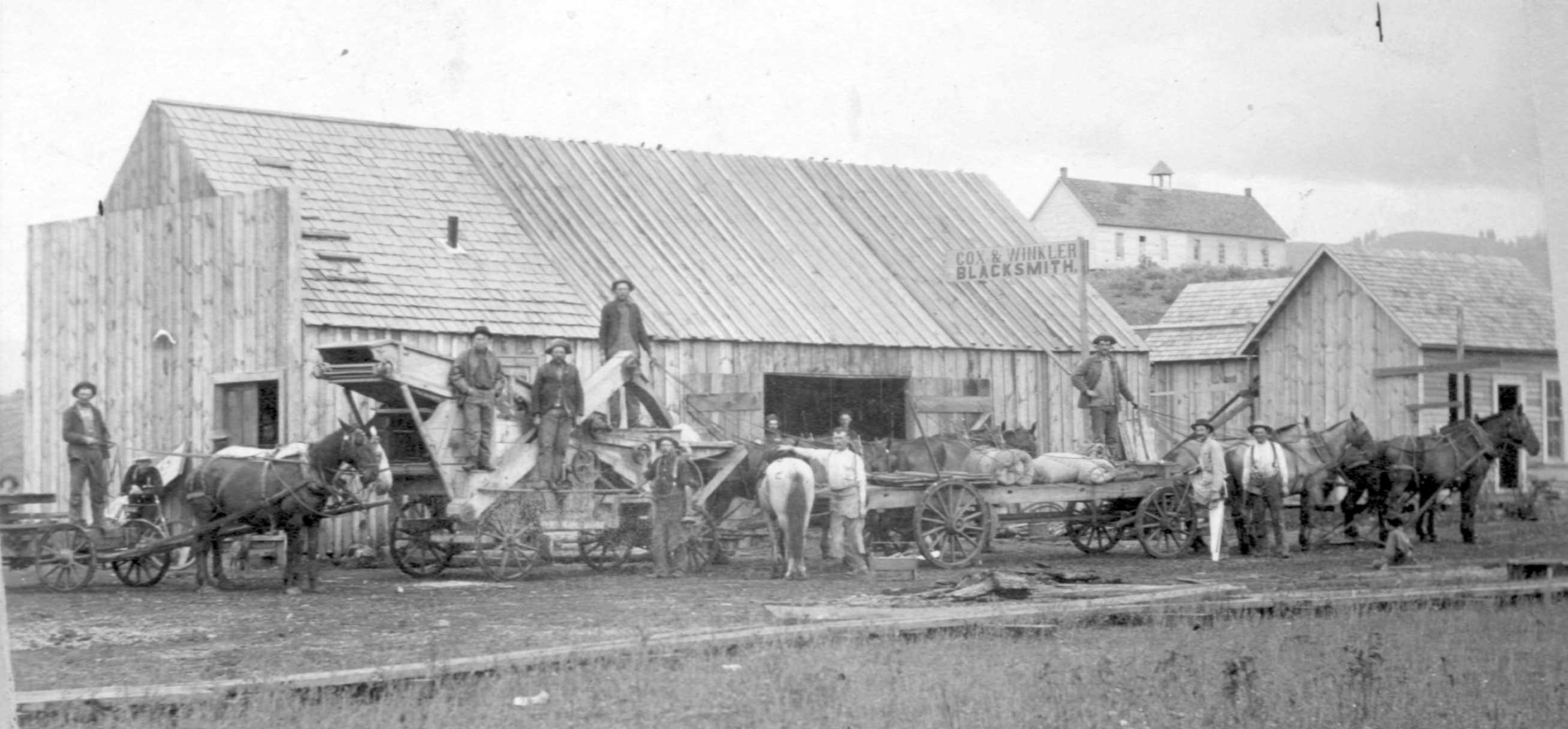 Winkler & Cox shop. Bill and Lewis Winkler were probably the main instigators of having this blacksmith shop built in 1899. This business was part of the migration of Council growth toward where the railroad depot was planned. Notice the new school on the hill in the background.