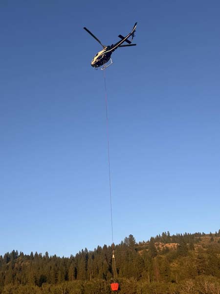 A USFS Helicopter gets water from a local stock pond to help fight the Camp Fire east of Council on private land. The fire was started by lightning on June 20 and discovered the next day. USFS crews were able to contain the fire to about 8.5 acres and was 100 contained by about 1PM on June 22. Photo credit: Katie Lynn Snyder.