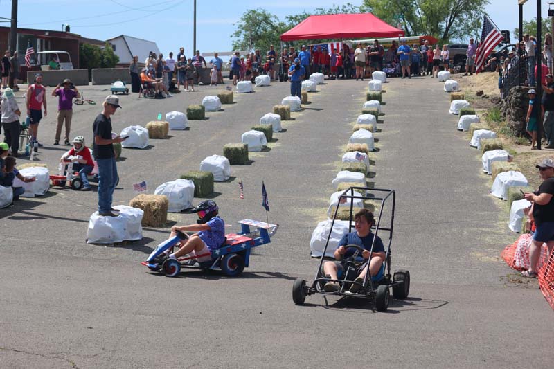 A racer crashes into a bale of hay (background, left) while another spins out after crossing the finish line during Council’s Soapbox Derby Race put on by the Council Chamber of Commerce on July 3.Photo credit: The Record Reporter.