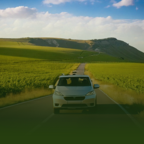Coche circulando por una carretera entre campos verdes