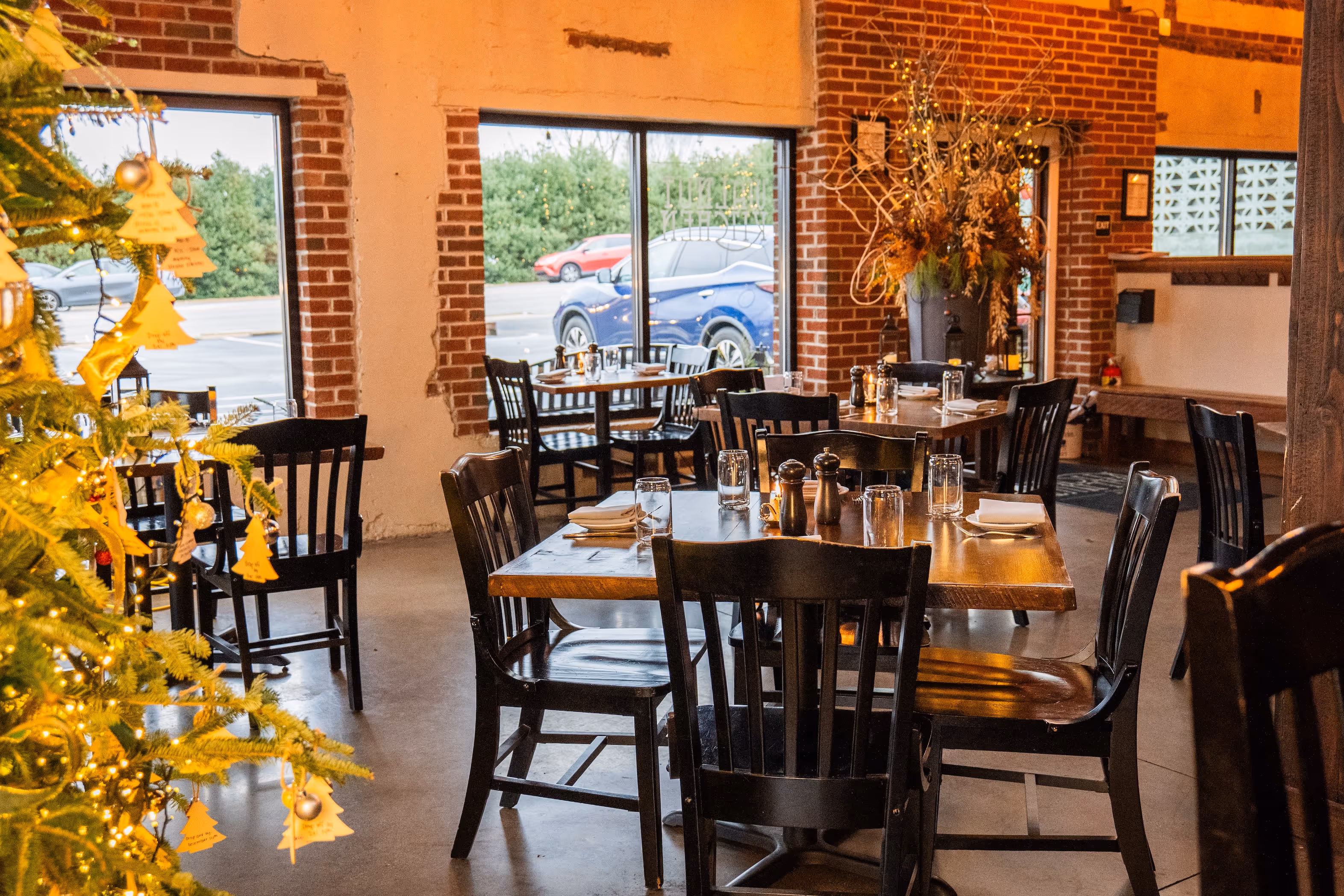 Grilled steak topped with green herb sauce and microgreens served with crispy French fries on a white plate in a restaurant setting.