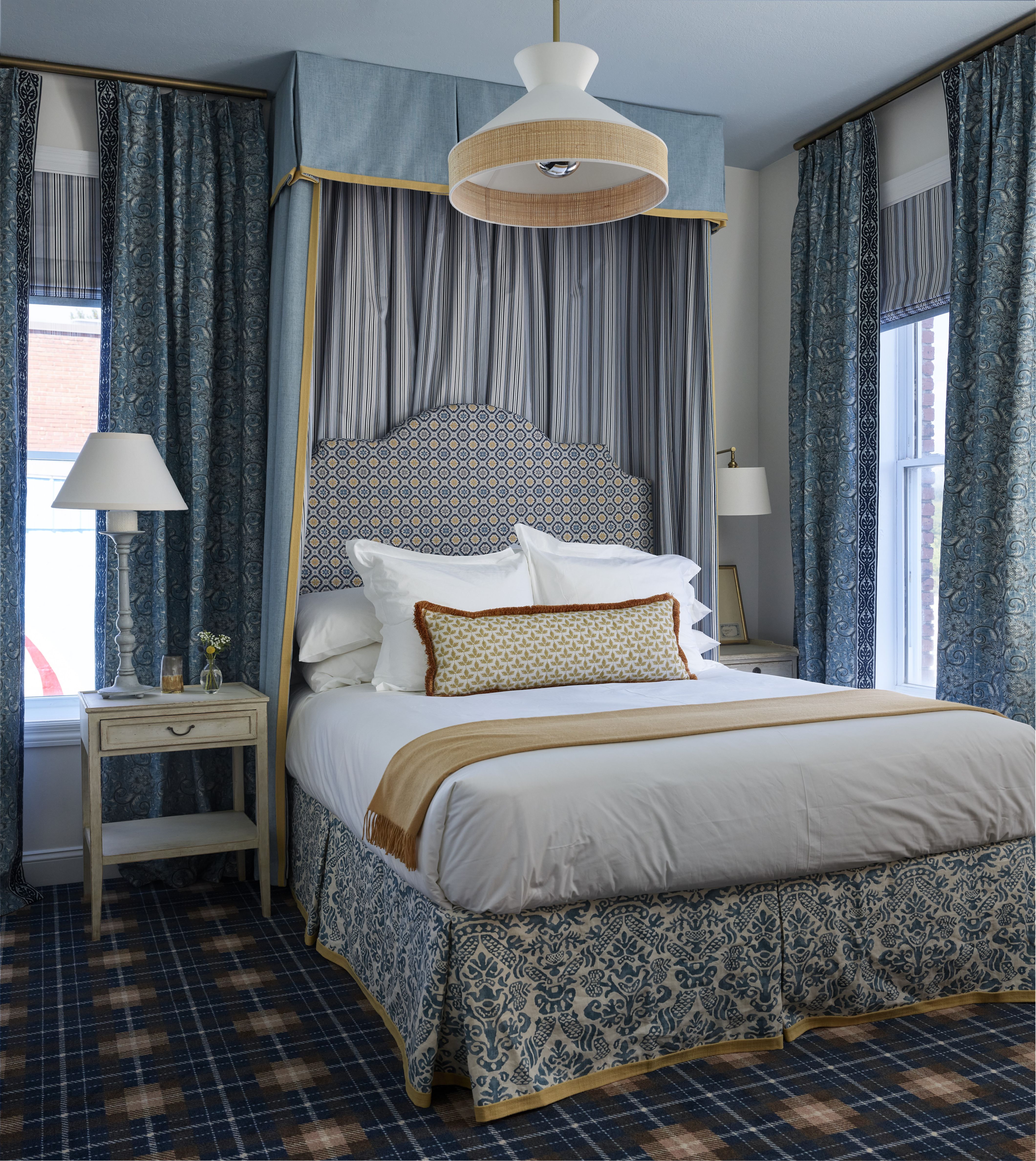 Plate of gourmet food with two pieces of seared meat topped with crushed nuts, served with pickled onions, mashed orange vegetables, and mustard sauce on a wooden table beside a blue candle and salt and pepper shakers.