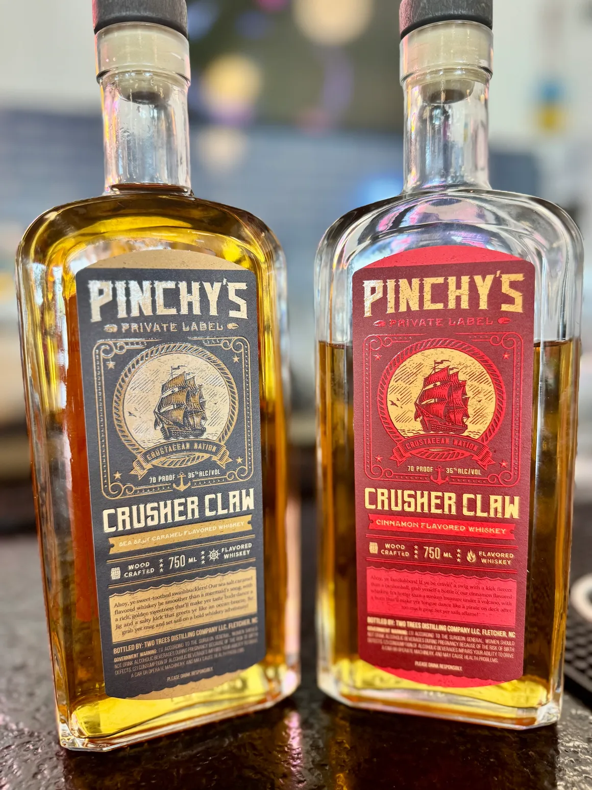 Dimly lit dining area with wooden tables and chairs, featuring a wall-mounted lantern lamp and a dark painting of a stag with antlers.