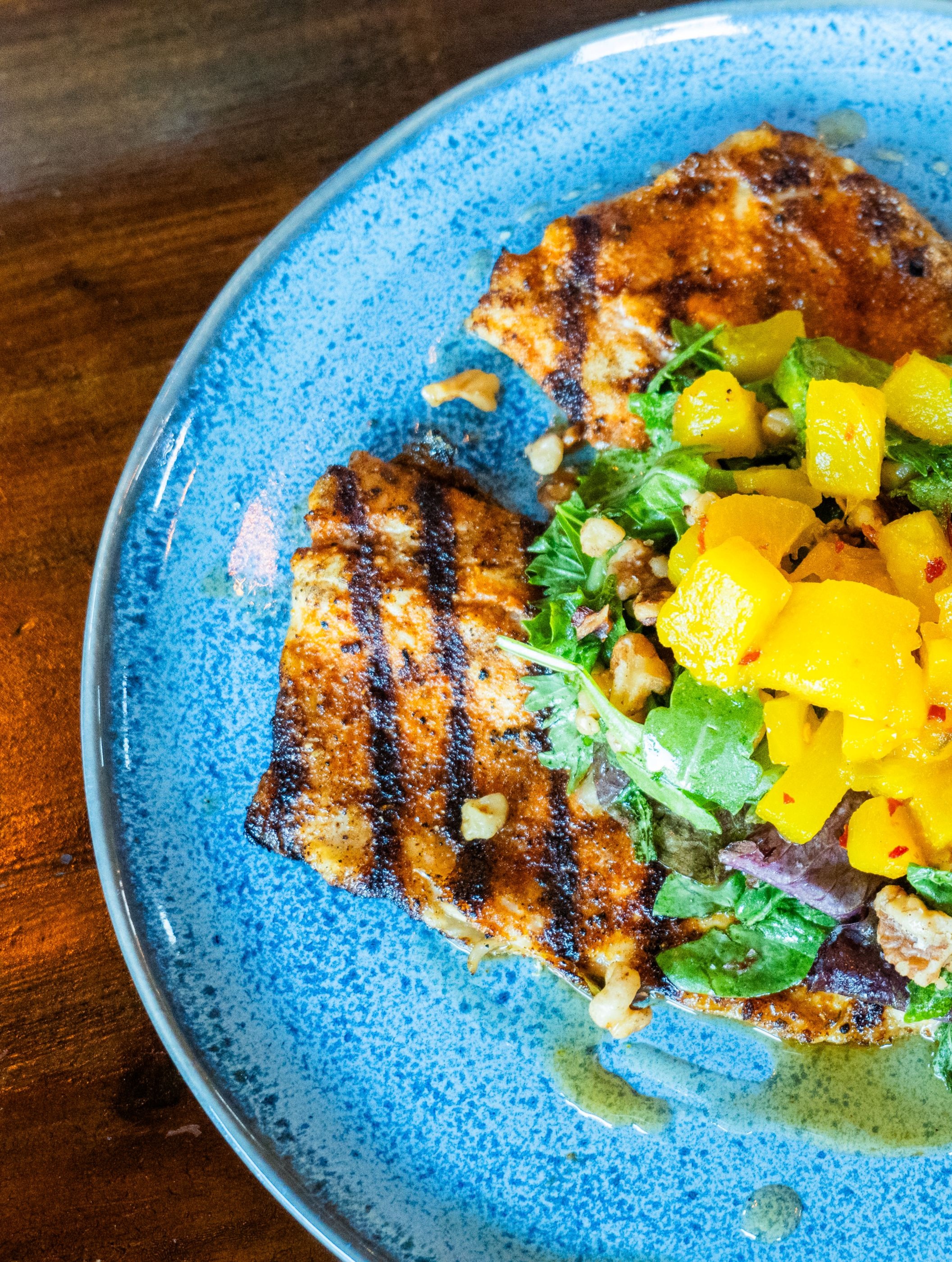 Salad with fried chicken pieces, mixed greens, cherry tomatoes, shredded cheddar cheese, pickled onions, and a side of ranch dressing.