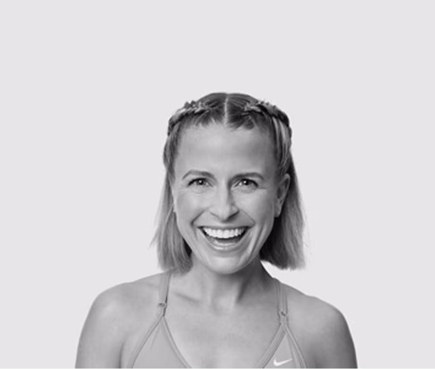Smiling woman with braid headband and short hair wearing a sports top.