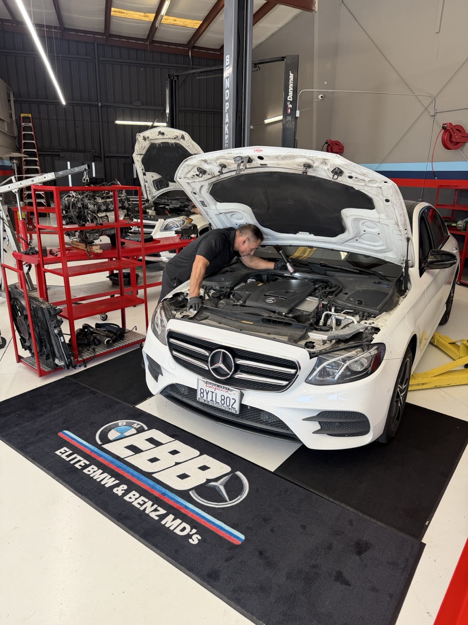 Technician working under the hood of a Mercedes-Benz E-Class at EBB in Fontana