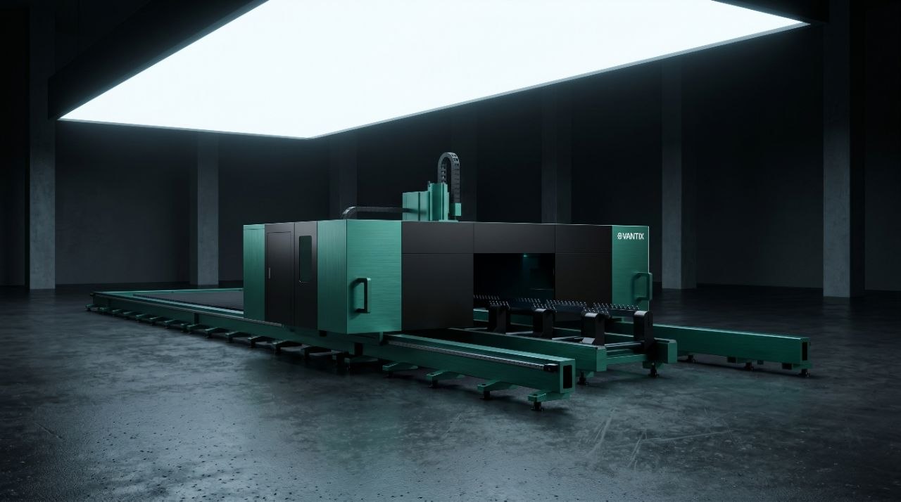 Rendering of a large teal and black Vantix laser cutting machine with long loading rails in a dark hall