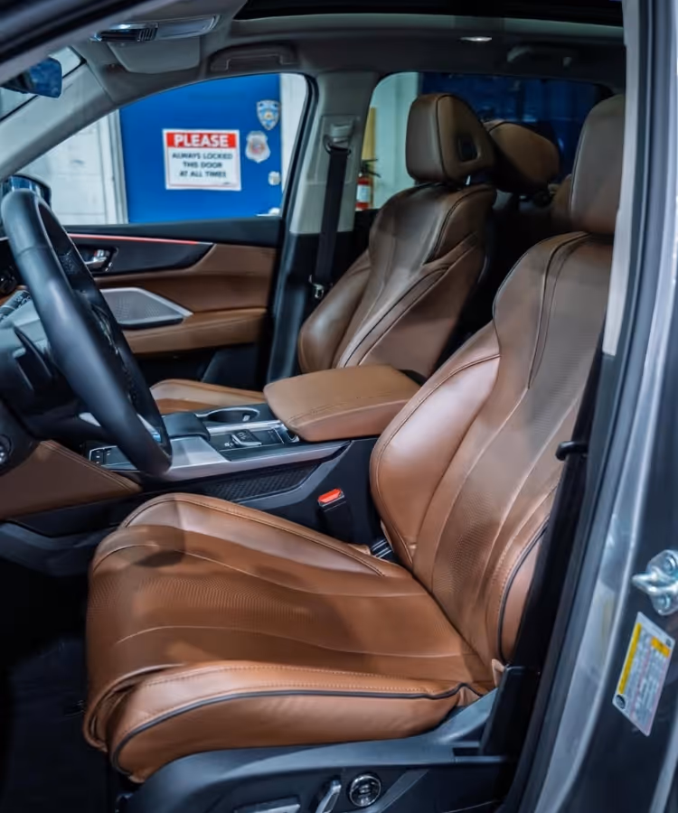 Side view of a car interior showing brown leather seats and part of the steering wheel.