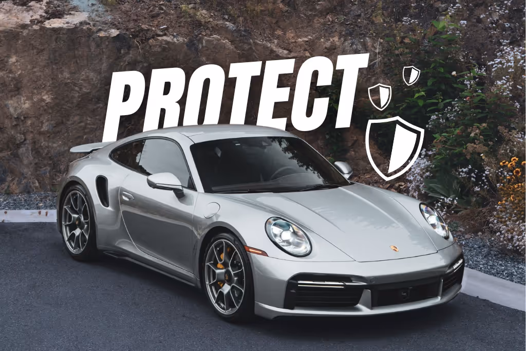 Silver Porsche sports car parked near a rock wall with word PROTECT and shield icons above it.