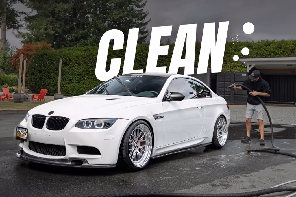 White BMW sports car being washed outdoors with large text CLEAN above it.