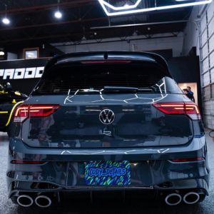 Back view of a dark Volkswagen R with quad exhausts inside a garage.