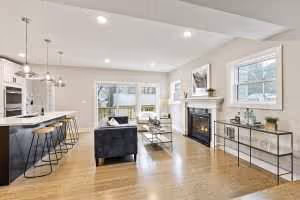 Open-concept kitchen overlooking living room with a large island, fireplace, and bright natural light in a Minneapolis remodel by Executive Remodeling