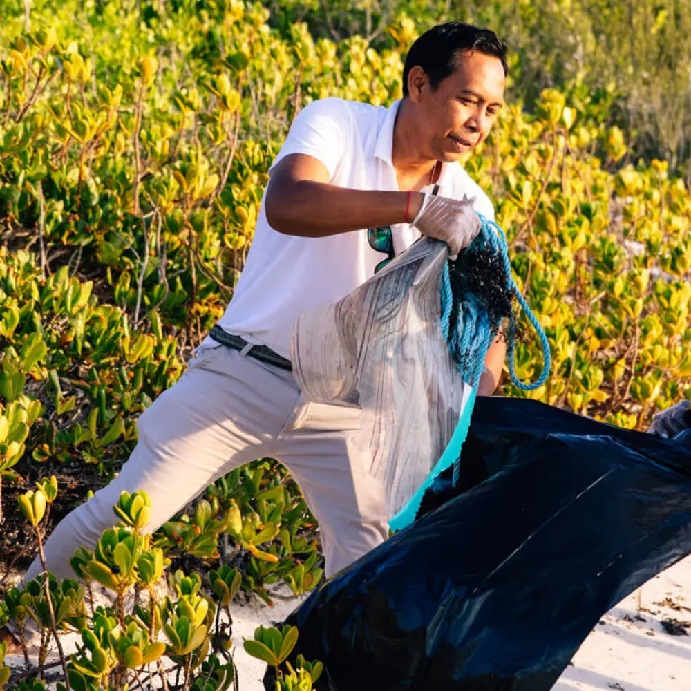 Dedicated staff member collecting litter to preserve the natural beauty of the Turks and Caicos coast.