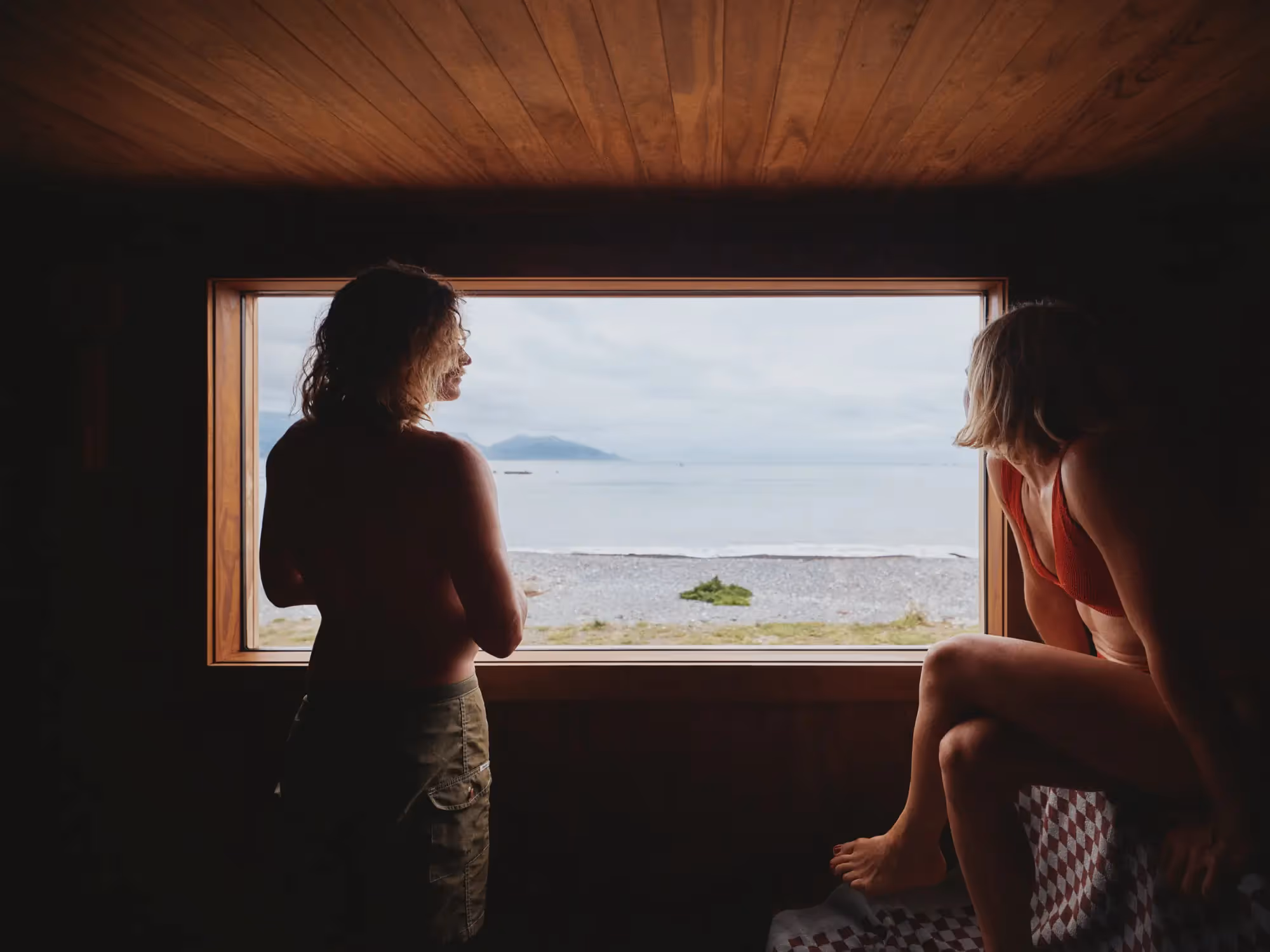 Tall waterfall cascading through dense green forest with large ferns in the foreground.