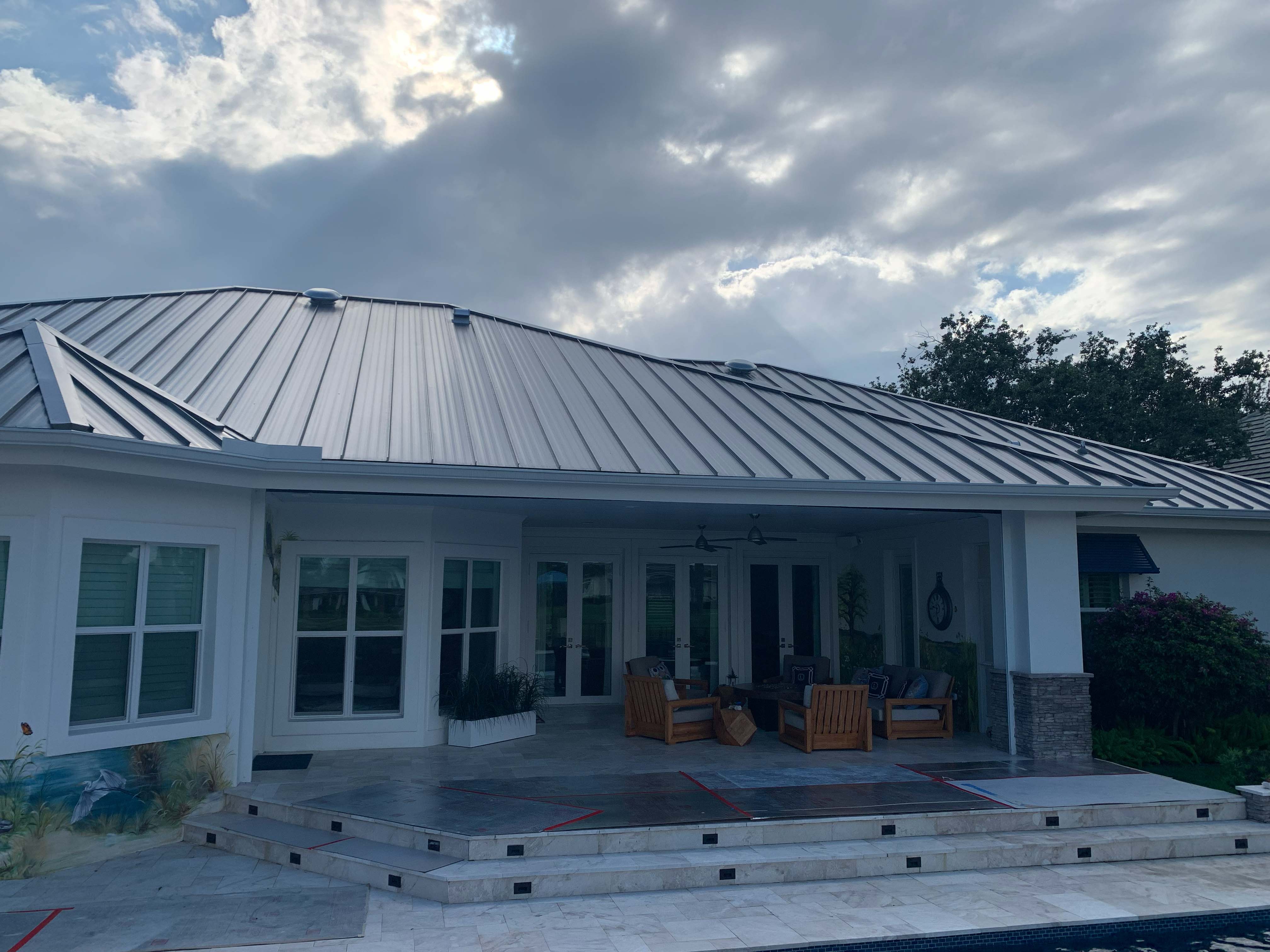Covered outdoor patio with wooden furniture under a metal roof.
