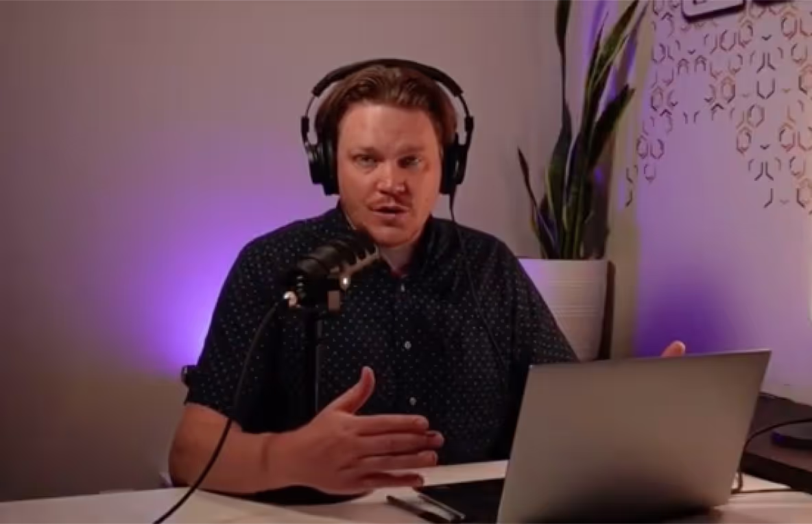 A man in front of his laptop talking to a microphone