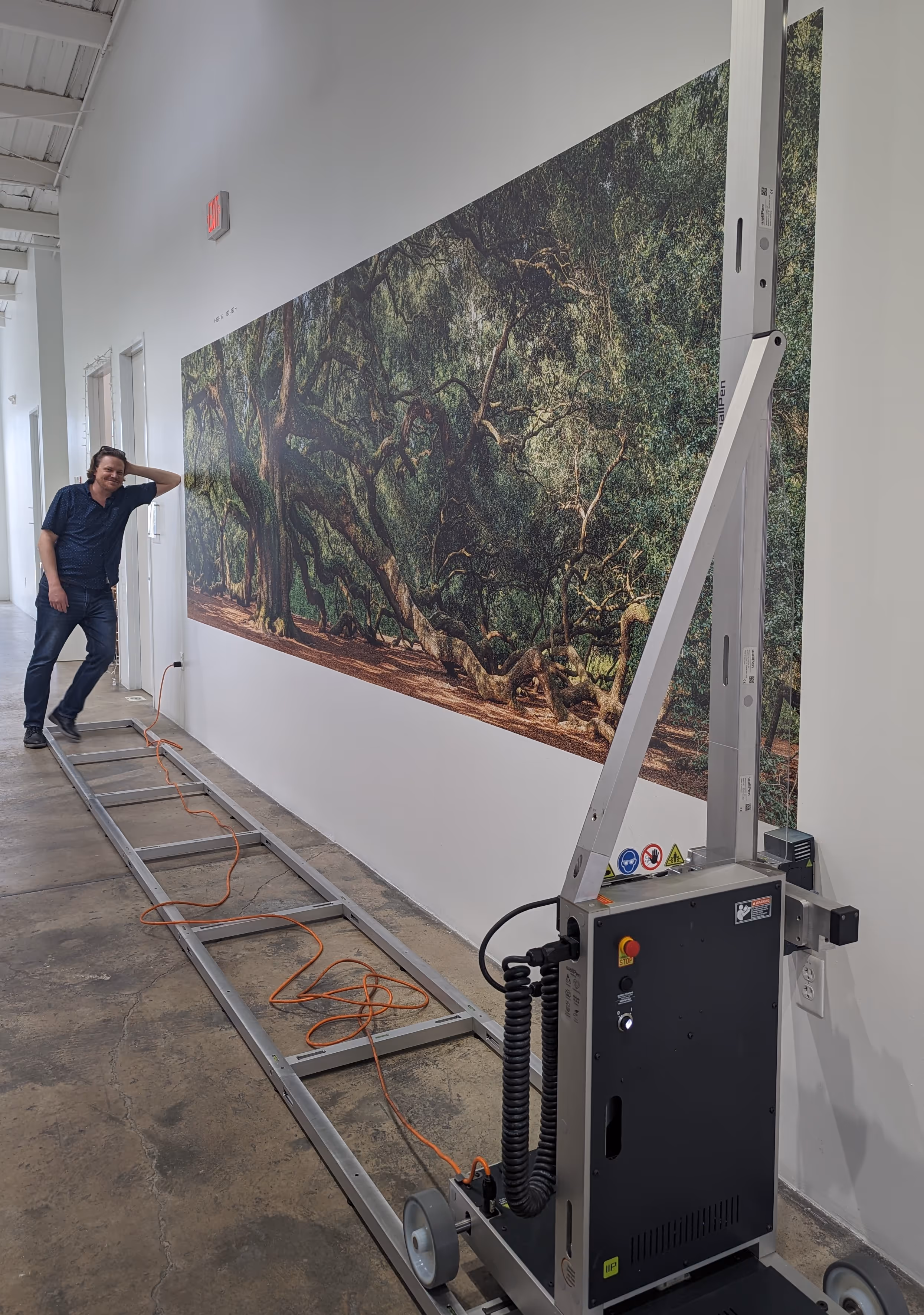 Mark leaning up against a wall with a printed mural of an Angel Oak on it