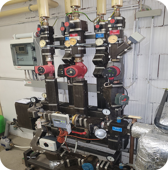 Industrielle Rohrleitungen mit Ventilen, Manometern und Pumpen in einem technischen Raum.