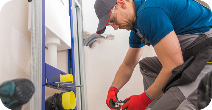 Installateur mit rotem Handschuh montiert Sanitärarmatur in einem Badezimmer.